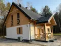 Nowy dom w lesie, drewniane elementy i biały tynk. Prowadzenie budowy domu zakończone sukcesem, gotowy do zamieszkania.