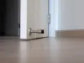 Metalowy odbojnik zamontowany na dole białych drzwi, zapobiegający ich trzaskaniu.