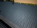 Nowoczesny dach pokryty ciemnoszarą blachą na rąbek, z widocznym kominem i oknem dachowym.
