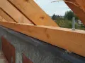 Drewniana murłata przymocowana do betonowej ściany za pomocą śrub.