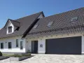 Nowoczesny dom z garażem i ciemnym dachem. Kąt nachylenia dachu 10 stopni zapewnia estetyczny wygląd i dobrą ochronę.