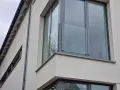 Nowoczesne portfenetry z przeszklonymi balustradami na jasnej elewacji.