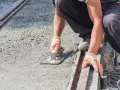 Robotnik wygładza świeży beton, dbając o właściwe proporcje dla betonu B10.