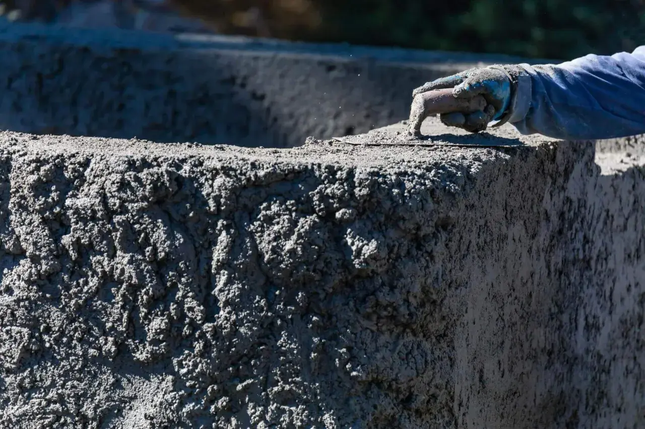 Ręka w rękawicy wygładza świeży beton C20/25. Sprawdź aktualną beton c20/25 cena za m3.