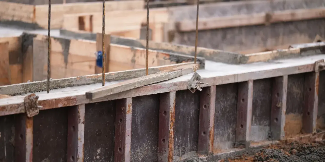 Drewniany szalunek czeka na beton. Widać zbrojenie i świeży beton.