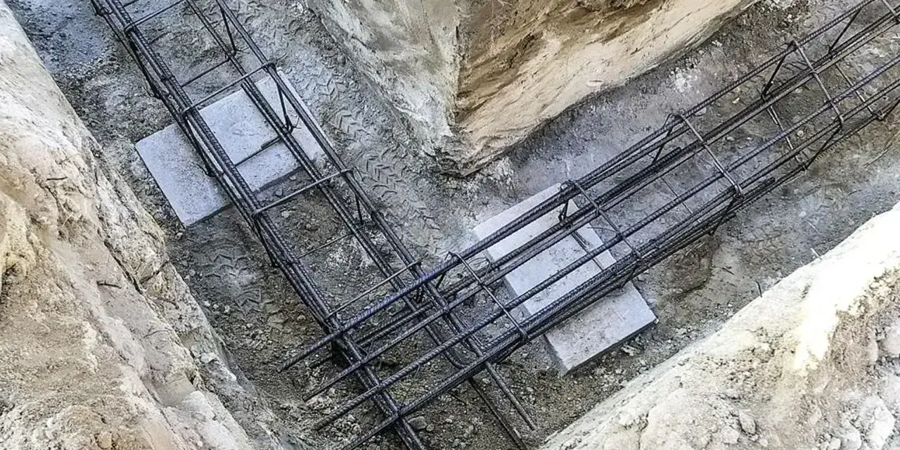 Zbrojenie płyty fundamentowej w wykopie. Stalowe pręty tworzą siatkę, gotową na zalanie betonem.