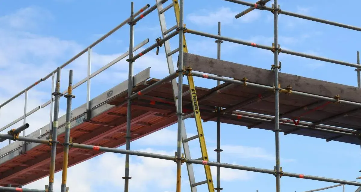 Rusztowanie aluminiowe z drabiną na tle błękitnego nieba.