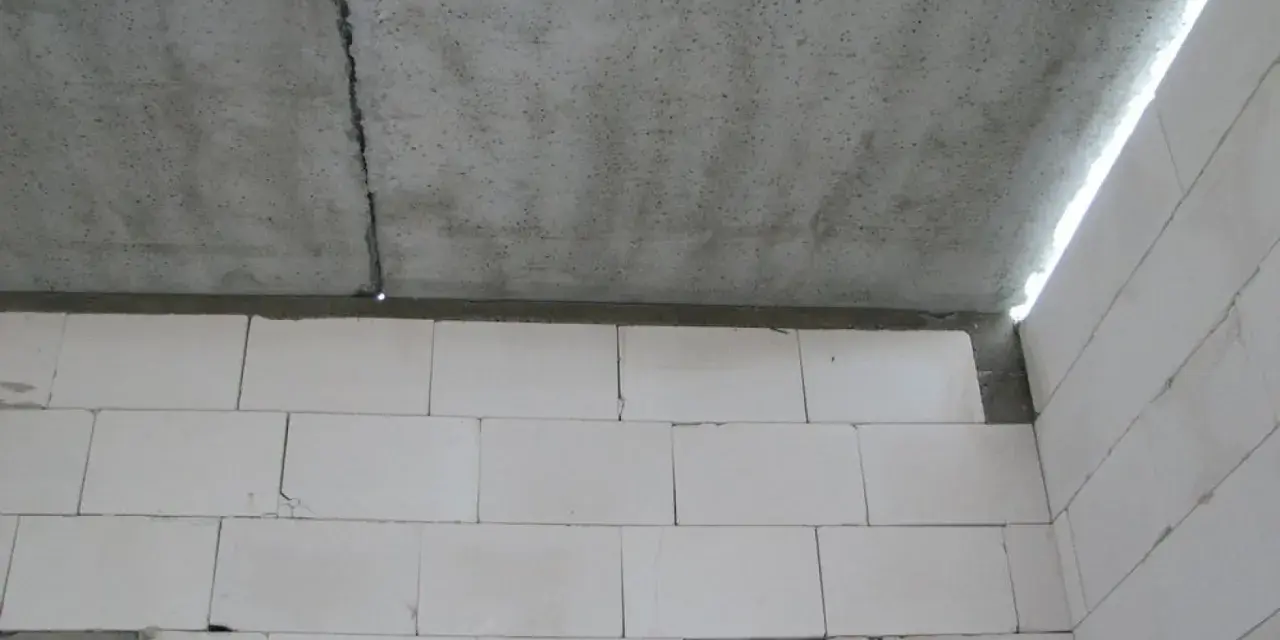 Betonowy strop z widocznym pęknięciem nad ścianą z białych pustaków.