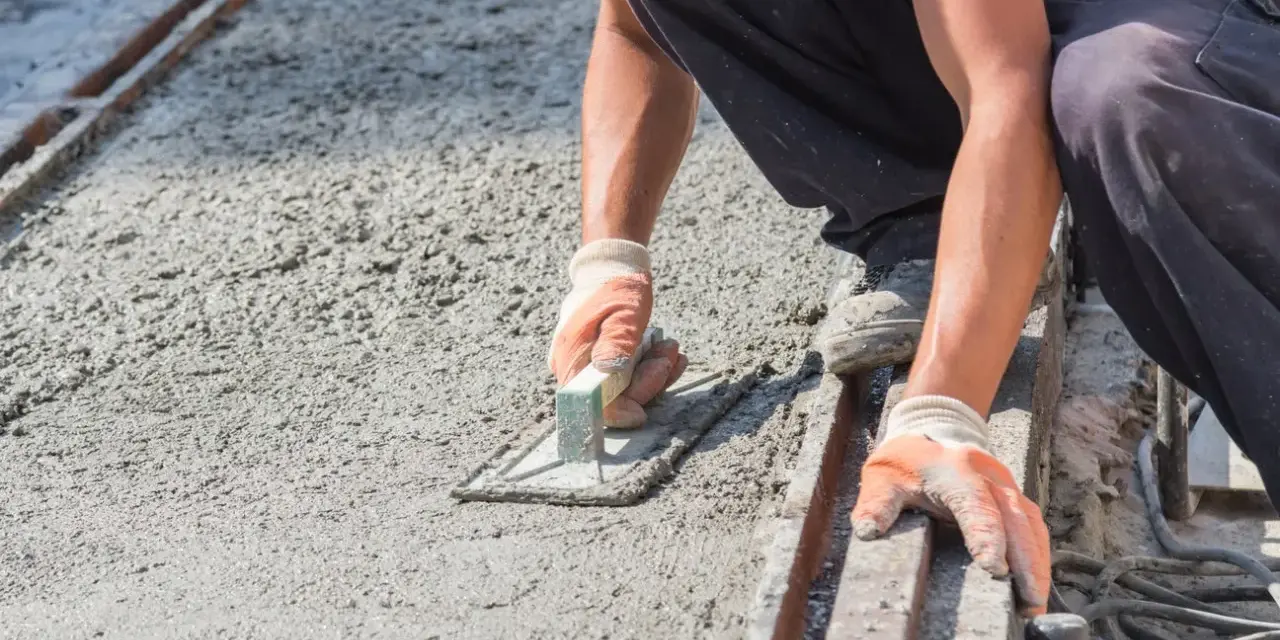 Robotnik wygładza świeży beton, dbając o właściwe proporcje dla betonu B10.