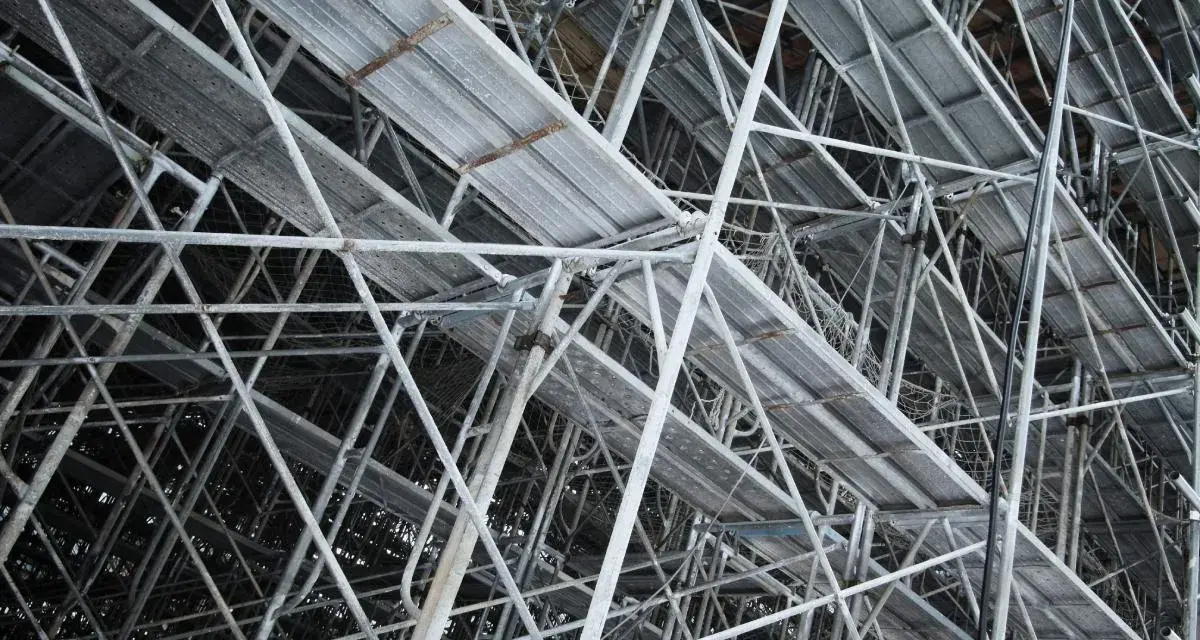 Skomplikowana konstrukcja rusztowania budowlanego z metalowymi platformami i wspornikami.