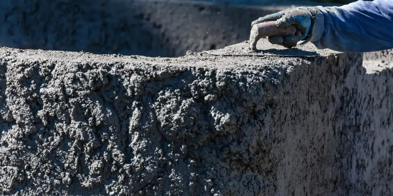 Ręka w rękawicy wygładza świeży beton C20/25. Sprawdź aktualną beton c20/25 cena za m3.