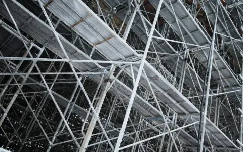Skomplikowana konstrukcja rusztowania budowlanego z metalowymi platformami i wspornikami.