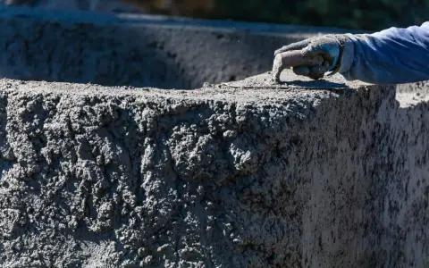 Ręka w rękawicy wygładza świeży beton C20/25. Sprawdź aktualną beton c20/25 cena za m3.