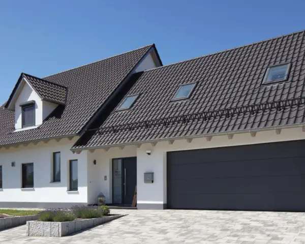 Nowoczesny dom z garażem i ciemnym dachem. Kąt nachylenia dachu 10 stopni zapewnia estetyczny wygląd i dobrą ochronę.