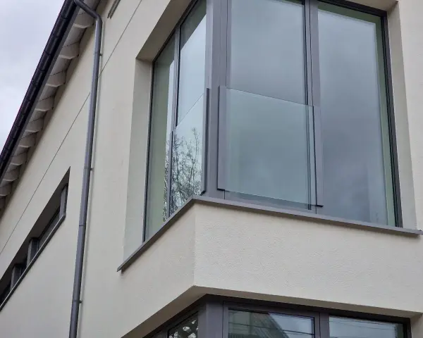 Nowoczesne portfenetry z przeszklonymi balustradami na jasnej elewacji.