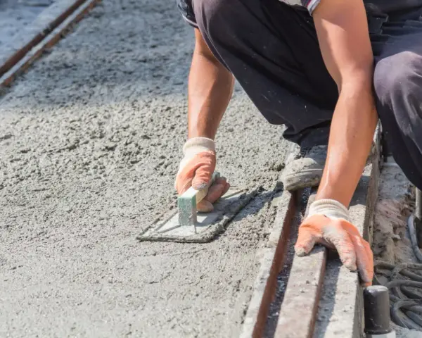 Robotnik wygładza świeży beton, dbając o właściwe proporcje dla betonu B10.