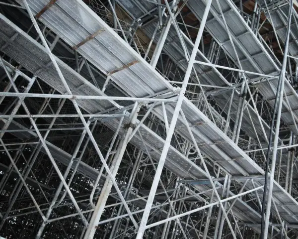 Skomplikowana konstrukcja rusztowania budowlanego z metalowymi platformami i wspornikami.