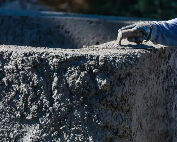 Ręka w rękawicy wygładza świeży beton C20/25. Sprawdź aktualną beton c20/25 cena za m3.