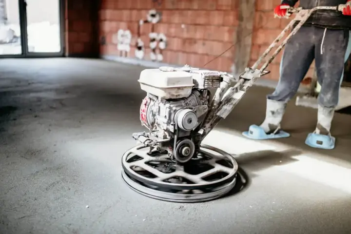 Pracownik wygładza wylewkę styrobetonową za pomocą mechanicznej zacieraczki. Sprawdź aktualną wylewka styrobeton cena za m2.