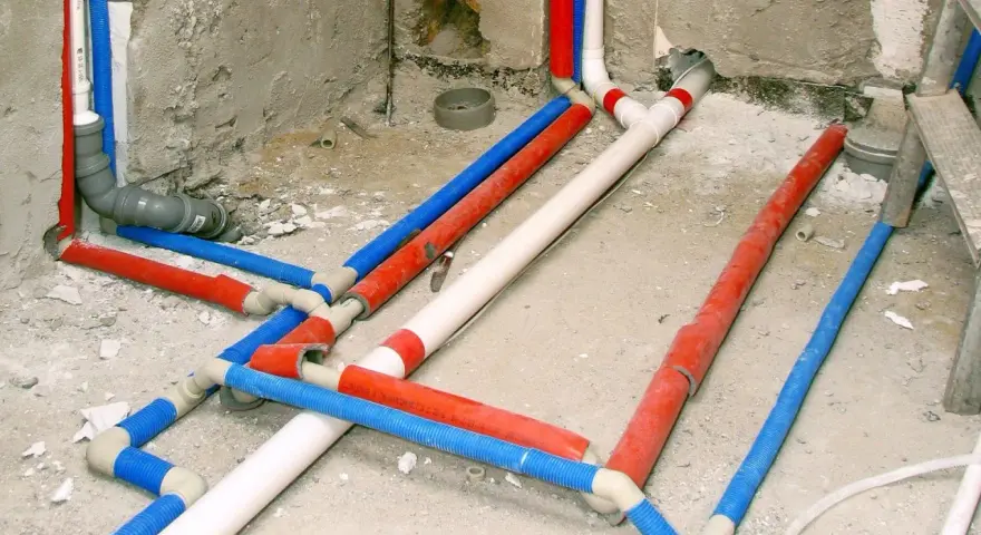Skomplikowana instalacja wodna w domu, z rurami czerwonymi, niebieskimi i białymi, przygotowana do ukrycia pod tynkiem.
