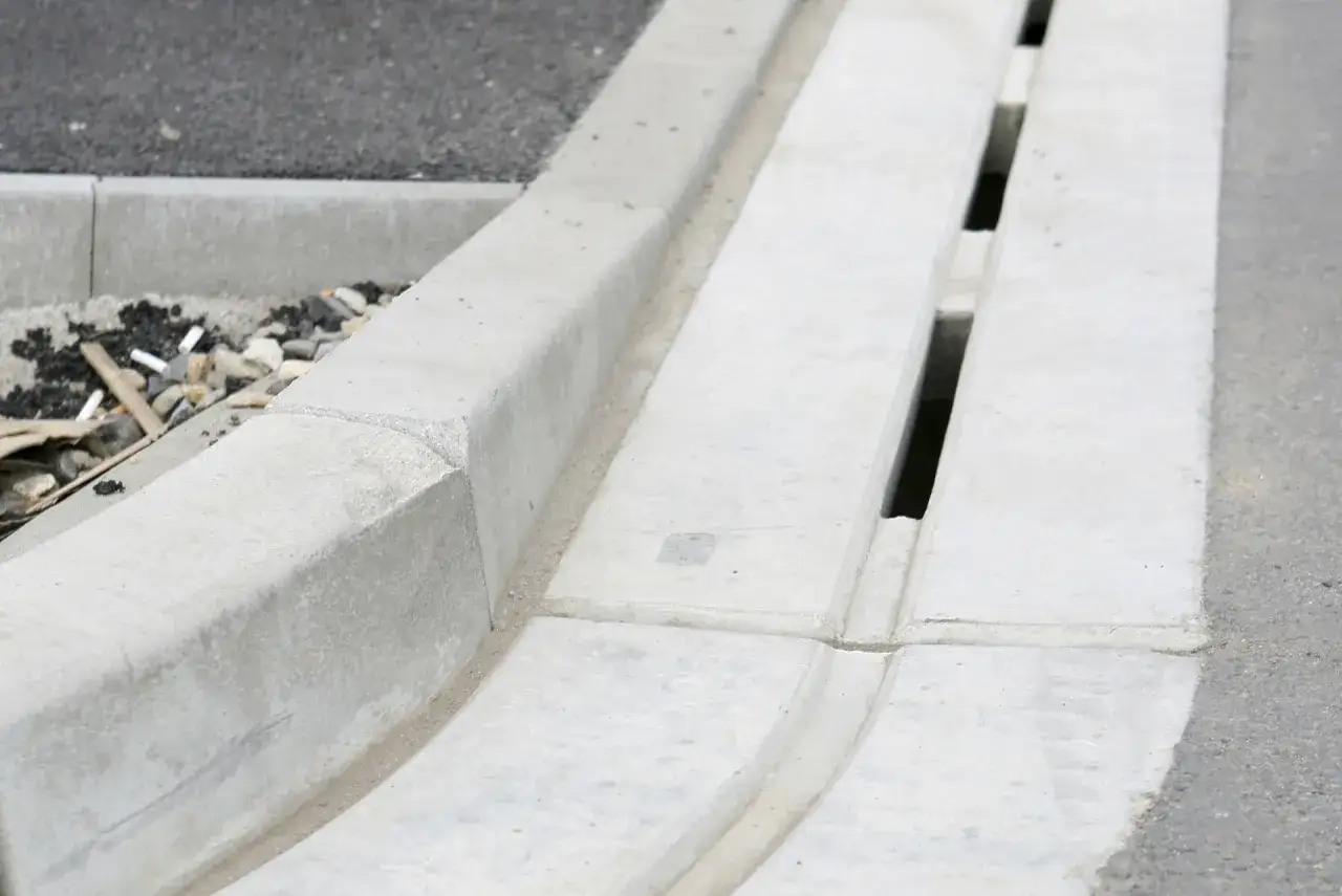 Betonowy krawężnik i system odprowadzania wody deszczowej z widoczną szczeliną dylatacyjną.