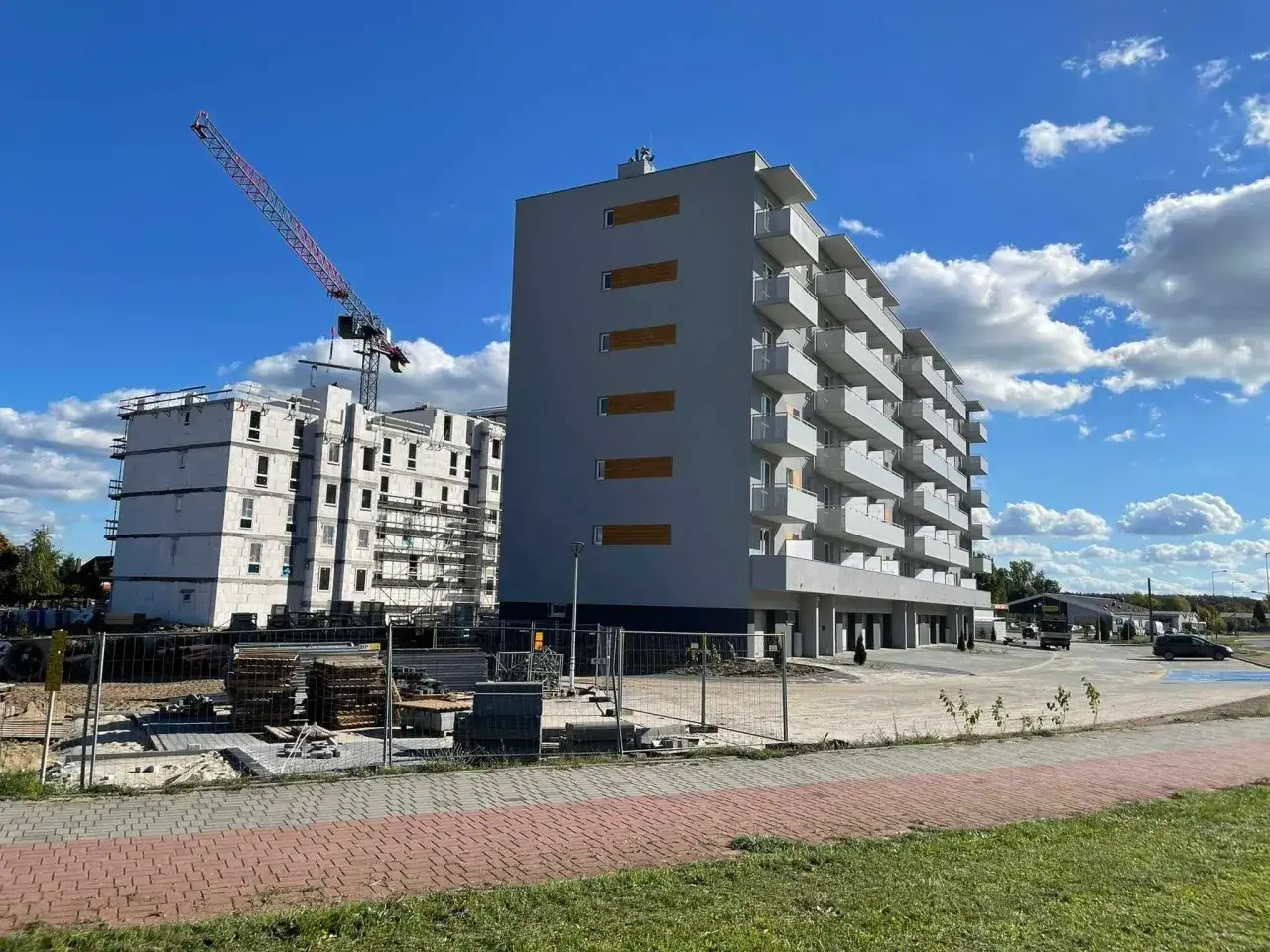 Budowa osiedla mieszkaniowego z dźwigiem budowlanym w tle.
