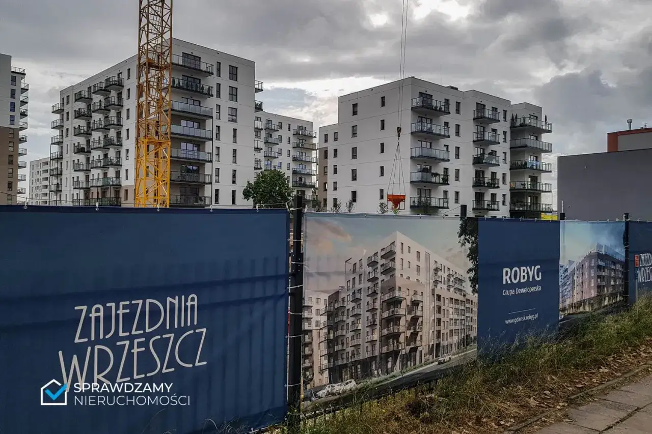 Budowa osiedla mieszkaniowego w Gdańsku, widoczne dźwigi i banery deweloperów.