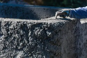 Ręka w rękawicy wygładza świeży beton C20/25. Sprawdź aktualną beton c20/25 cena za m3.